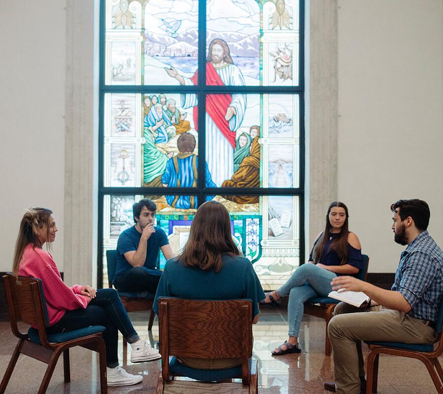 Ministry students sit in a circle and study the bible in a chapel.
